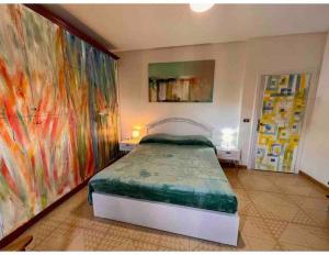 a bedroom with a bed with colorful paintings on the walls at La casa dell’artista di Vittorio Vertone in Pietragalla