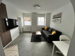 a living room with a black couch and a tv at Appartment Florida Nähe Düsseldorf, Messe, HBF, City, Netflix, WIFI, HELIOS Hospital in Krefeld