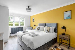 a bedroom with a large bed and a yellow wall at Waterside Cottage - Hot Tub, Mooring, Arcade, Bar in Neatishead