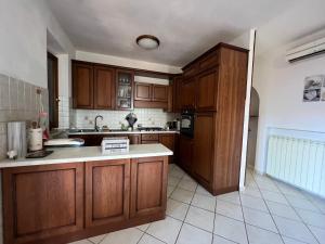 a kitchen with wooden cabinets and a white tile floor at Casa Isidora in Acquaviva