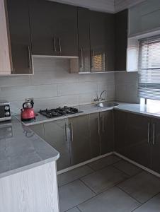 a kitchen with gray cabinets and a sink and a stove at Prison View Guesthouse 2 in Klerksdorp +28 photos