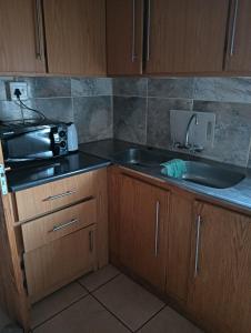 a kitchen with a sink and a microwave at Prison View Guesthouse 2 in Klerksdorp