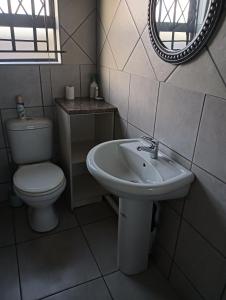 a bathroom with a toilet and a sink and a mirror at Prison View Guesthouse 2 in Klerksdorp