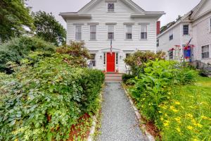 una casa blanca con una puerta roja y algunos arbustos en Quarters on Main, en Castine