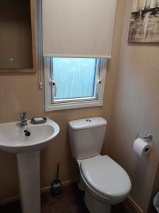 a bathroom with a toilet and a sink and a window at Happy place no4 in Ringwood