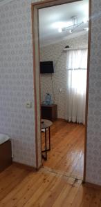 Гостевой дом Анастасия في سوخومي: غرفة بطاولة ونافذة وغرفة ذات أرضيات خشبية