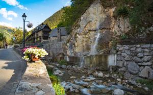einen Wasserfall an der Seite einer Steinmauer mit Blumen in der Unterkunft ERA CASETA in Tredós