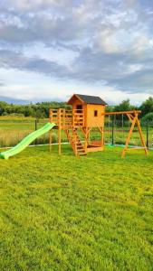 a playground with a green slide in a field at Domki "Na Dziedzinie" z Gorącą Balią in Szaflary