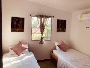 2 Betten in einem Zimmer mit Fenster in der Unterkunft La lila in San Bernardo del Viento