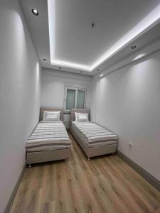 2 Betten in einem Zimmer mit weißen Wänden und Holzböden in der Unterkunft Ilıca Side Site İçerisinde in Manavgat