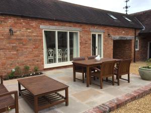 a patio with a wooden table and chairs at Middle Wymson House in Stratford-upon-Avon