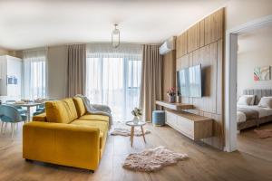a living room with a yellow couch and a bedroom at Chic Central Oradea -Netflix, Parcare, Self Check-in, Balcon in Oradea
