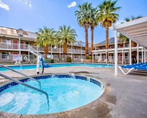 a swimming pool with palm trees and a resort at Clarion Inn Ridgecrest in Ridgecrest