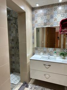une salle de bain avec un lavabo et une douche avec un miroir dans l'établissement Luxueux appartement pied dans l'eau sur la plage d'Imi Ouaddar, à Agadir nʼ Aït Sa