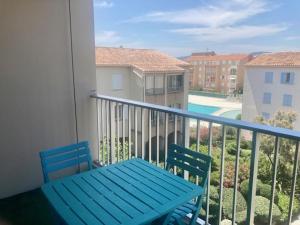 un banco azul en un balcón con vistas a la piscina en Joli Appartement au Lagon bleu, en Fréjus
