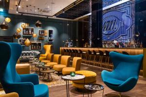 Un restaurante con sillas azules y un bar. en Motel One Köln-Altstadt, en Colonia