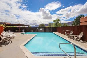a swimming pool with chairs and a table and a fence at Castillo De Las Rocas 3396 in Moab