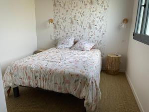 a small bedroom with a bed with a floral bedspread at Gîte des 5 cépages avec jacuzzi 3 étoiles in LʼÉtoile