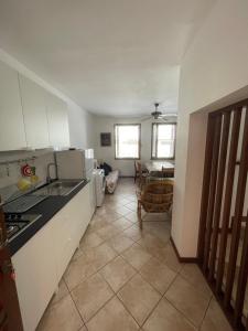 eine Küche mit weißen Schränken und einem Fliesenboden in der Unterkunft Casa Corbatto Family Apartment in Grado in Grado