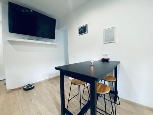 czarny stół z dwoma stołkami w pokoju z telewizorem w obiekcie Mieuxqualhotel jacuzzi privatif Le carré w mieście Bordeaux