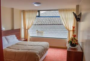 a bedroom with a bed and a large window at HOTEL FLOR DE LOS ANDES in Tulcán