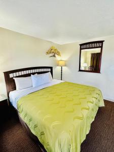 um quarto com uma cama grande e um cobertor amarelo em Sage N Sand Motel em Moses Lake