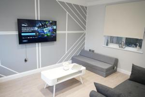 a living room with a couch and a tv on a wall at Ricoh Arena/Newly Refurbished Semi-Detached House in Coventry
