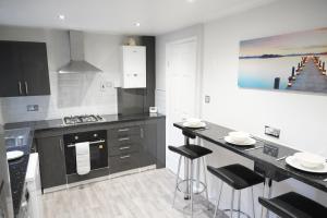a kitchen with black and white appliances and a counter at Ricoh Arena/Newly Refurbished Semi-Detached House in Coventry