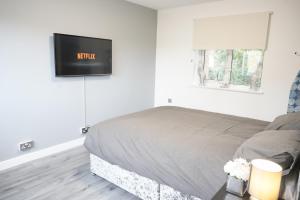 a bedroom with a bed with a tv on the wall at Ricoh Arena/Newly Refurbished Semi-Detached House in Exhall