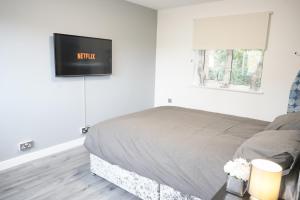 a bedroom with a bed with a tv on the wall at Ricoh Arena/Newly Refurbished Semi-Detached House in Coventry