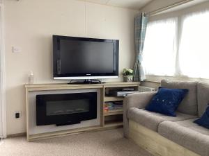 a living room with a flat screen tv and a couch at Leysdown Little Escapes in Leysdown-on-Sea