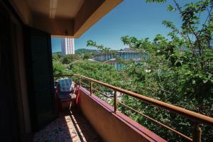 einen Balkon eines Hauses mit einem Stuhl und Bäumen in der Unterkunft Apartament near the center of city 2 in Vlorë
