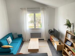 sala de estar con sofá azul y ventana en Appartement T2 avec accès piscine, en Pérols