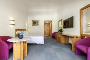 a hotel room with a bed and two purple chairs at Hotel Rancho San Diego Grand Spa Resort in Ixtapan de la Sal