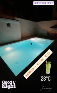 una grande piscina con un drink in esso di Scirocco Holiday House DIAMANTE a Rosolini