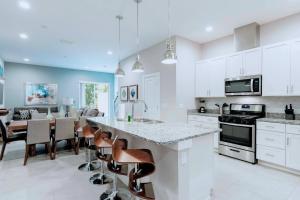 a kitchen with white cabinets and a table and chairs at Gorgeous 4 Suites DREAM Villa 5 min to Disney in Orlando