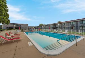 Una gran piscina con sillas y un edificio. en HomeTowne Studios by Red Roof Painted Post, en Painted Post
