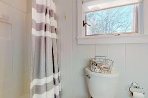 a bathroom with a shower curtain and a toilet at Lakeside Cottages on Toddy Pond in Orland