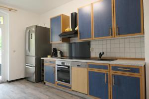 a kitchen with blue cabinets and a stainless steel refrigerator at Ländlicher Rückzugsort im Herzen von Mühlhausen in Mühlhausen