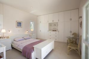 a white bedroom with a bed and a table at Villa Waterfront in Souvala