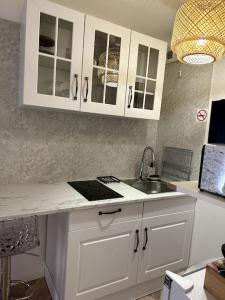 a kitchen with white cabinets and a sink at Appartement cosy avec balcon et piscine in Besançon