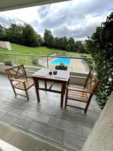 a patio with a table and two chairs and a pool at Appartement cosy avec balcon et piscine in Besançon