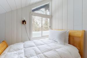 ein weißes Bett in einem Zimmer mit Fenster in der Unterkunft Chalet at Shawnee in Bridgton