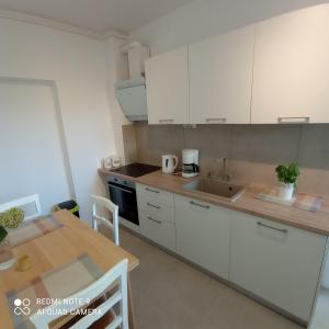 a kitchen with white cabinets and a wooden table at Apartment MONAS I in Pješčana Uvala 