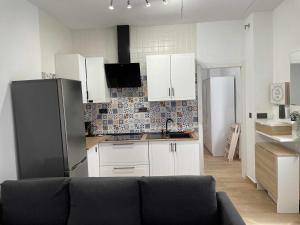 a kitchen with white cabinets and a black refrigerator at Sunlight Málaga Centro in Málaga