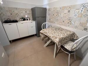 a small kitchen with a table and a refrigerator at Albemarooms in Noto