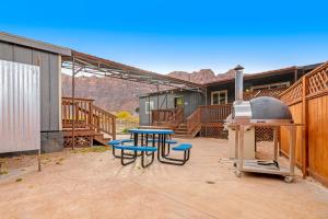 a patio with a grill and picnic tables and chairs at Spanish Valley Vineyard - Both homes in Moab