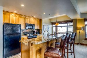 cocina con nevera negra y armarios de madera en Sundial Lodge #316B, en Park City