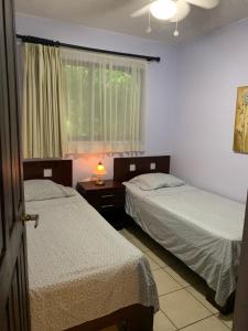 a bedroom with two beds and a window with a lamp at Cocomarindo Condo #72 in Coco