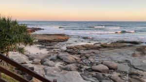 a beach with rocks and the ocean at sunset at Ocean View 3 bedroom entire house central of Caloundra in Caloundra West